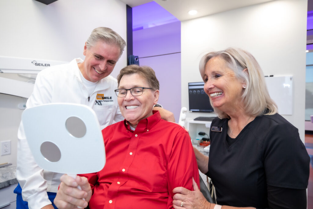 dr thompson smiling with a patient who received full mouth dental implants.